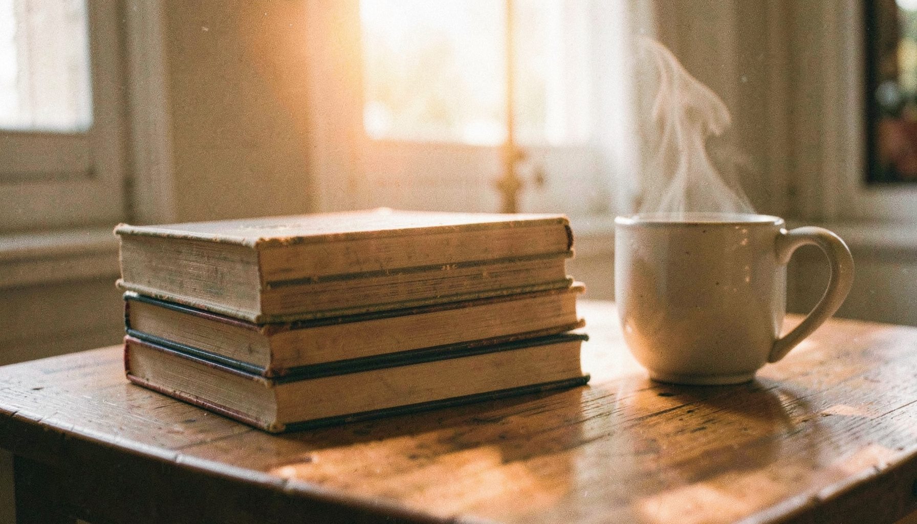 A warm, softly lit stack of well-worn hardcover books resting on a wooden table beside a steaming mug, with gentle morning light filtering through a window. The mood is quiet, reflective, and inviting.